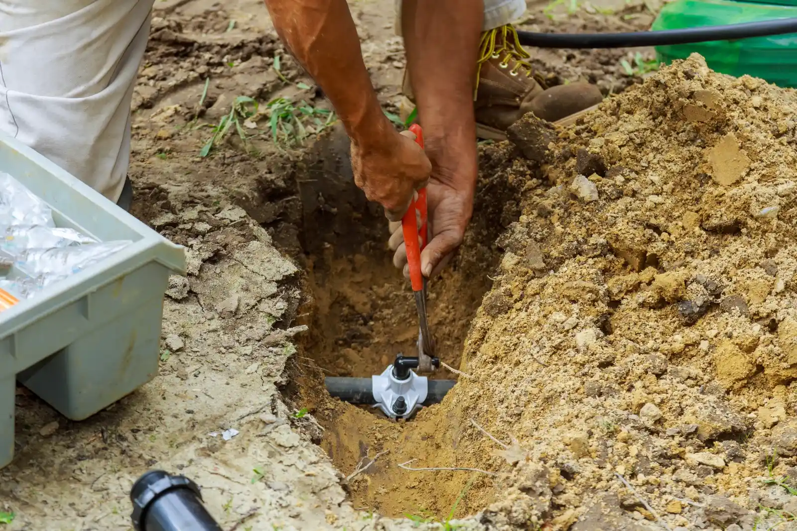 A person uses a wrench on a pipe fitting during outdoor sprinkler installation in Palm Beach County, FL.