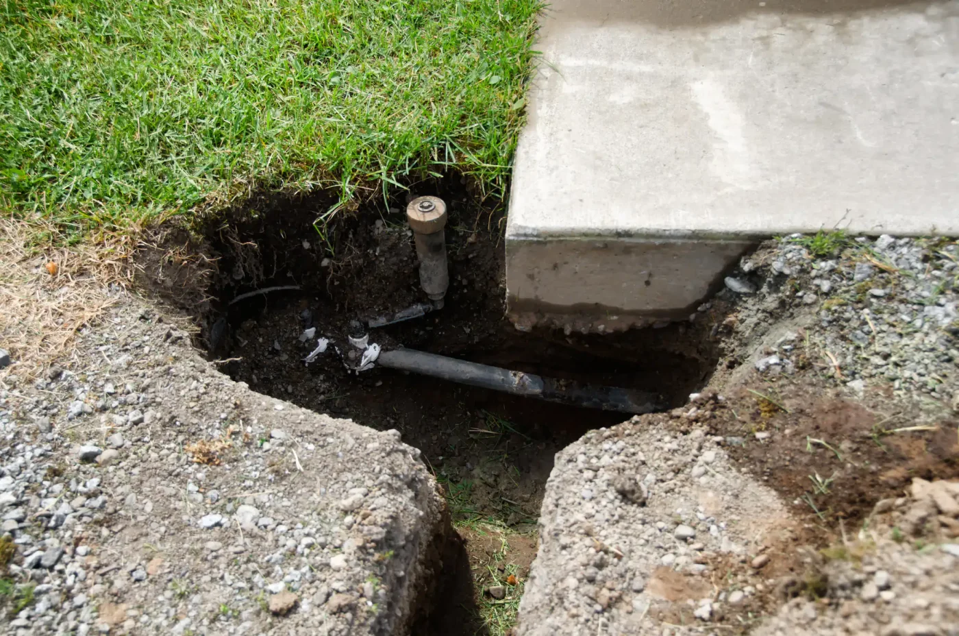A broken sprinkler pipe is visible in a dug hole, showing a common sprinkler installation issue in Palm Beach County, FL.