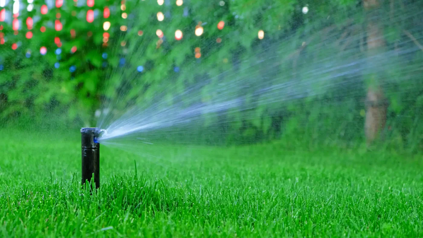 A garden sprinkler sprays water onto lush green grass, illustrating modern sprinkler systems Palm Beach County, FL.