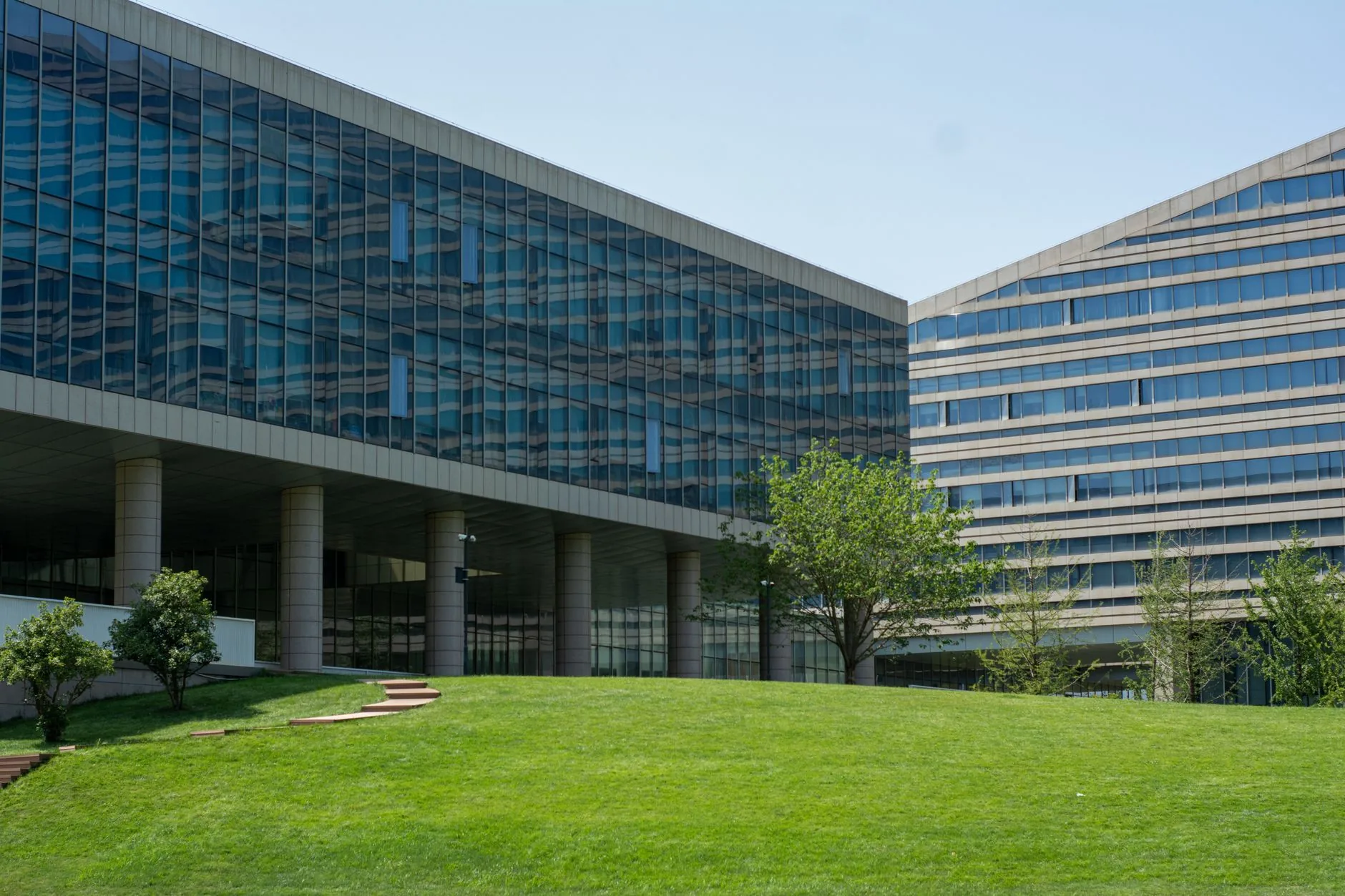 Modern office buildings in FL with glass windows face a lush lawn, maintained by Palm Beach County, FL sprinklers.