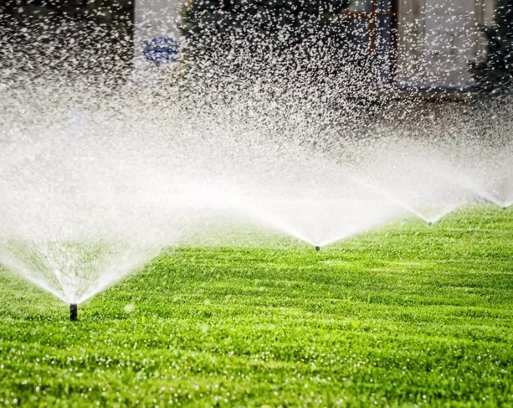 Sprinklers water a lush green lawn under the Florida sun, demonstrating Palm Beach County, FL sprinkler systems.